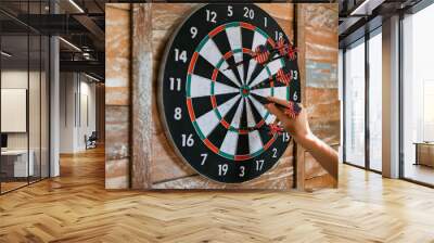 Game of darts. Close-up female hand pulls a dart from a target. Wall mural