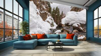 Spring, snow on the banks of a mountain river, forest and mountains, snow melting. Wall mural