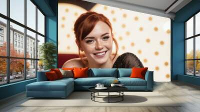 Portrait of a young attractive woman with short red hair and a bright smile having fun in a nightclub. Wall mural