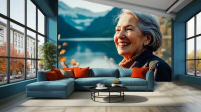 Portrait of an elderly woman with a bright smile on the shore of a lake in the mountains. Autumn landscape. Wall mural