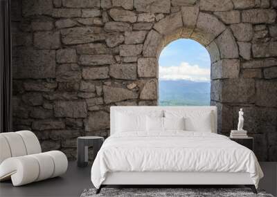 Stone war tower window with motion blurred bird and sea coast view with green tree hills Wall mural