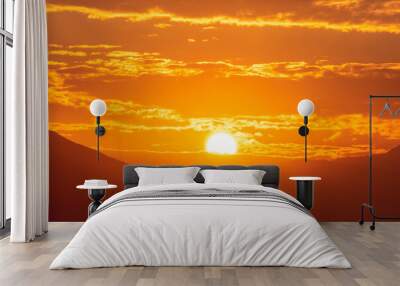 Sunset sky with orange clouds. A beautiful, colorful, abstract mountain landscape with sun in a orange tonality. Nature sky background. Sky sunset in the morning with colorful orange sunlight. Wall mural