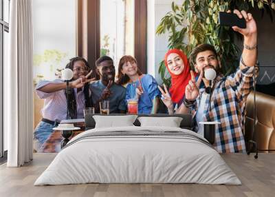 Group of happy friends making selfie on smartphone together in cafe. Wall mural