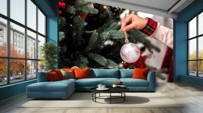 Little child's hand decorating Christmas tree indoors. Wall mural