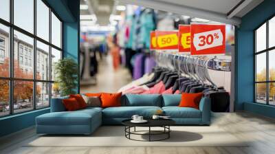 A red stand with a big discount at the mall. Advertising clothes on Black Friday.The concept of a seasonal sale with clothes hangers in the background. Wall mural