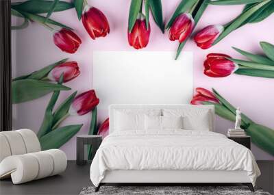 Red tulips are laid out in the heart on a pink background with a postcard.  Wall mural