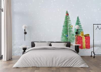 Two toy Christmas trees and a red gift box on the snow.  Wall mural