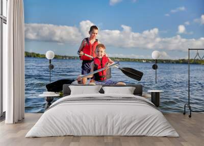 Boys having fun on a paddle board. Summer camp activity Wall mural