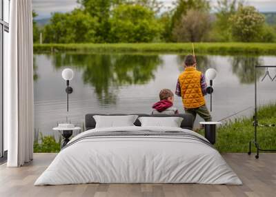 children fishing on the shore of the lake. brothers hold fishing rods Wall mural