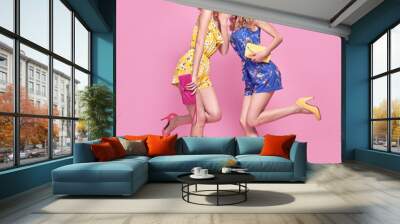 Two Young carefree Woman in stylish playsuit having fun. Beautiful fashionable model girl in trendy summer outfit. Graceful friends with fashion hairstyle, make up on pink. Creative funny concept Wall mural