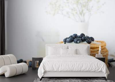 Traditional Russian thin pancakes with condensed milk and blueberries on a white background Wall mural