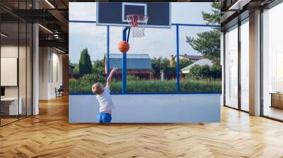 Little boy playing basketball outdoors at summer day Wall mural