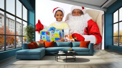 a black man, an African American in Santa Claus costume, sits in a chair. Child girl sitting on Santa's lap Wall mural