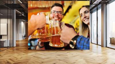 Friends clink glasses of beer glasses close-up on the background of the pub Wall mural