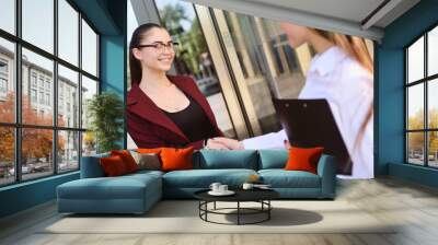 two girls managers smile and shake hands after signing a contract or a successful deal Wall mural