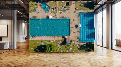 Aerial view of a two large and crowded outdoor pool. People swim in blue water pool top view on a summer day. Pool in green park. Wall mural