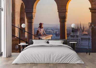 A happy young woman enjoying her trip to the Castle of Budapest in Hungary on the view point from Fisherman Bastion on sunrise. Wall mural