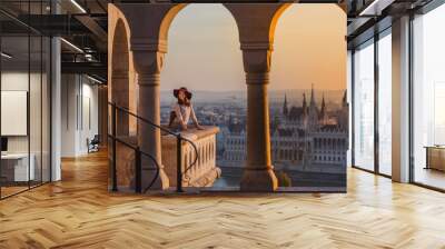 A happy young woman enjoying her trip to the Castle of Budapest in Hungary on the view point from Fisherman Bastion on sunrise. Wall mural