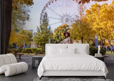 A happy young woman travel by bicycle and stop near the Budapest Eye big Ferris wheel in Budapest Wall mural