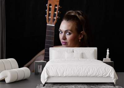 girl in a red dress sits on the floor near the guitar on a black background Wall mural