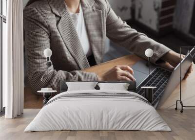 Woman hands typing on touchpad computer, working remote online. Faceless business woman working on laptop at workplace in a trendy modern office with the table Wall mural