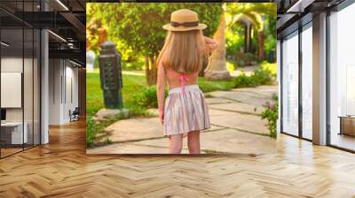 Close-up back of an adorable little girl with long blond hair in a tropical resort, palm up on a sunny summer day Wall mural