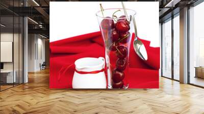 milk jug with a ribbon  glass of cherry and spoon on a red backg Wall mural