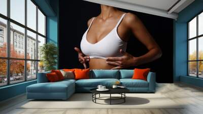 Slim sporty girl front taned body in white underwear straightens the top under the bust close-up with the black background text space around Wall mural