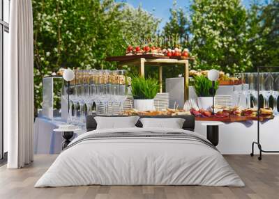 buffet in the open air - canapes and glasses against the background of flowering trees and the sky Wall mural