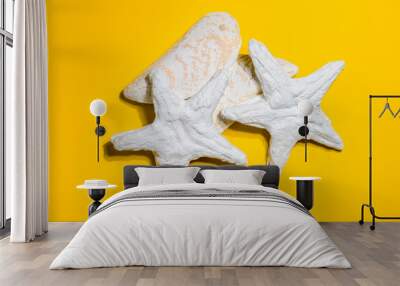 Starfishes and pebbles. The composition of plaster figures on yellow background. Wall mural