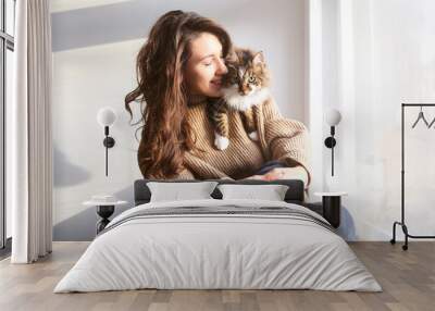 Charismatic young woman playing with her adorable cat. Wall mural