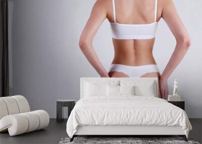 Close up shot of unrecognizable fit woman in lingerie isolated on white background. Cropped shot of lower half of slim attractive female's body in white underwear. Copy space for text. Wall mural