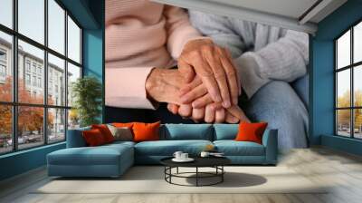 Cropped shot of elderly woman and female geriatric social worker holding hands. Women of different age comforting each other. Close up, background, copy space. Wall mural