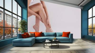 Cropped shot of woman's legs after body hair removal procedures. Unrecognizable woman showing her calves over isolated white background. Copy space for text, close up. Wall mural