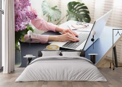 Feminine freelance workspace concept. Woman's hands typing on white laptopp with black keyboard, desk with matte blue table top. Freelance blogger writing an article. Close up, copy space for text. Wall mural