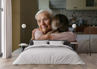 Grandmother and granddaughter hugging in the living room. Two adult women of different age. Family values concept. Close up, copy space, background. Wall mural