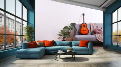 Minimalistic interior design concept. Acoustic guitar on grey textile sofa in spacious room of loft style apartment with wood textured laminated flooring. Background, copy space, close up. Wall mural