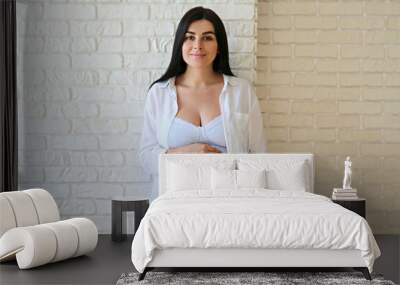 Portrait shot of young beautiful woman on third trimester of pregnancy. Close up of pregnant female with arms on her round belly. Expecting a child concept. Background, copy space. Wall mural