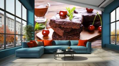 Square pieces of homemade brownies, dark chocolate spread paste, cherry & pecan nut on wooden table. High calorie pastry. Cocoa based sweets, bad for figure. Close up, copy space background, top view. Wall mural