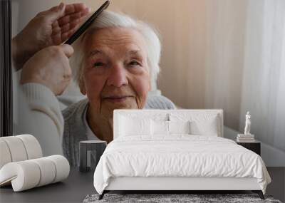 Unrecognizable female expressing care towards an elderly lady, brushing her hair with a comb. Granddaughter helping granny with a haircut. Family values concept. lose up, copy space, background. Wall mural