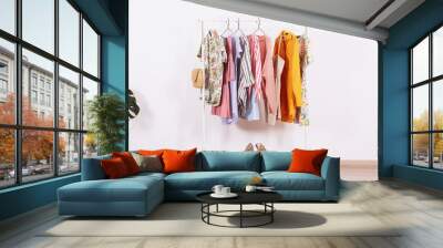 Women's hip clothing store interior concept. Row of different colorful female clothes hanging on rack in hipster fashion show room in shopping mall. White wall background. Copy space. Wall mural