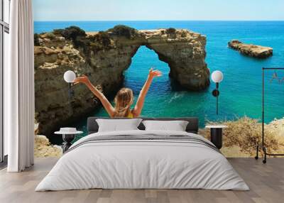 Young beautiful woman enjoying the panoramic top view of rocky beaches with cliffs somwhere, somwhere in Algarve, Portugal. Atlantic ocean shore background. Copy space for text. Wall mural