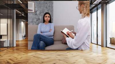 Young woman in distress on a psychological therapy session. A conversation between psychologist and her client in the office. Copy space, background. Wall mural