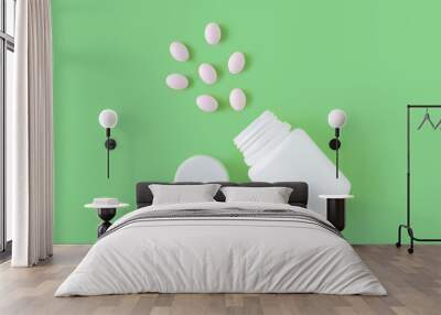 White pills and bottle on green background. Medical pharmacy concept. Probiotics benefits. Wall mural