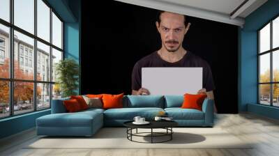 angry young man portrait with a white copy space on his hands over a black background Wall mural