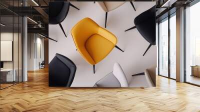 A bright yellow chair captures attention in a circle of stylish black and neutral seating arranged on a light floor Wall mural