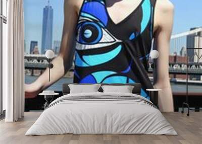 A model showcases chic urban fashion with a bold graphic print dress on a sunny waterfront promenade, with the city skyline in the backdrop. Wall mural