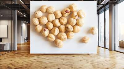 Heart shaped bunch of roasted hazelnuts on white background Wall mural