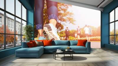 Young fitness woman legs walking with group of people exercise walking in the city public park in morning. Wall mural