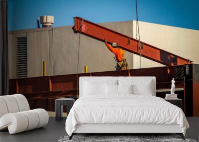 A consruction worker directing placement of a large steel beam that is atttached to a crane Wall mural